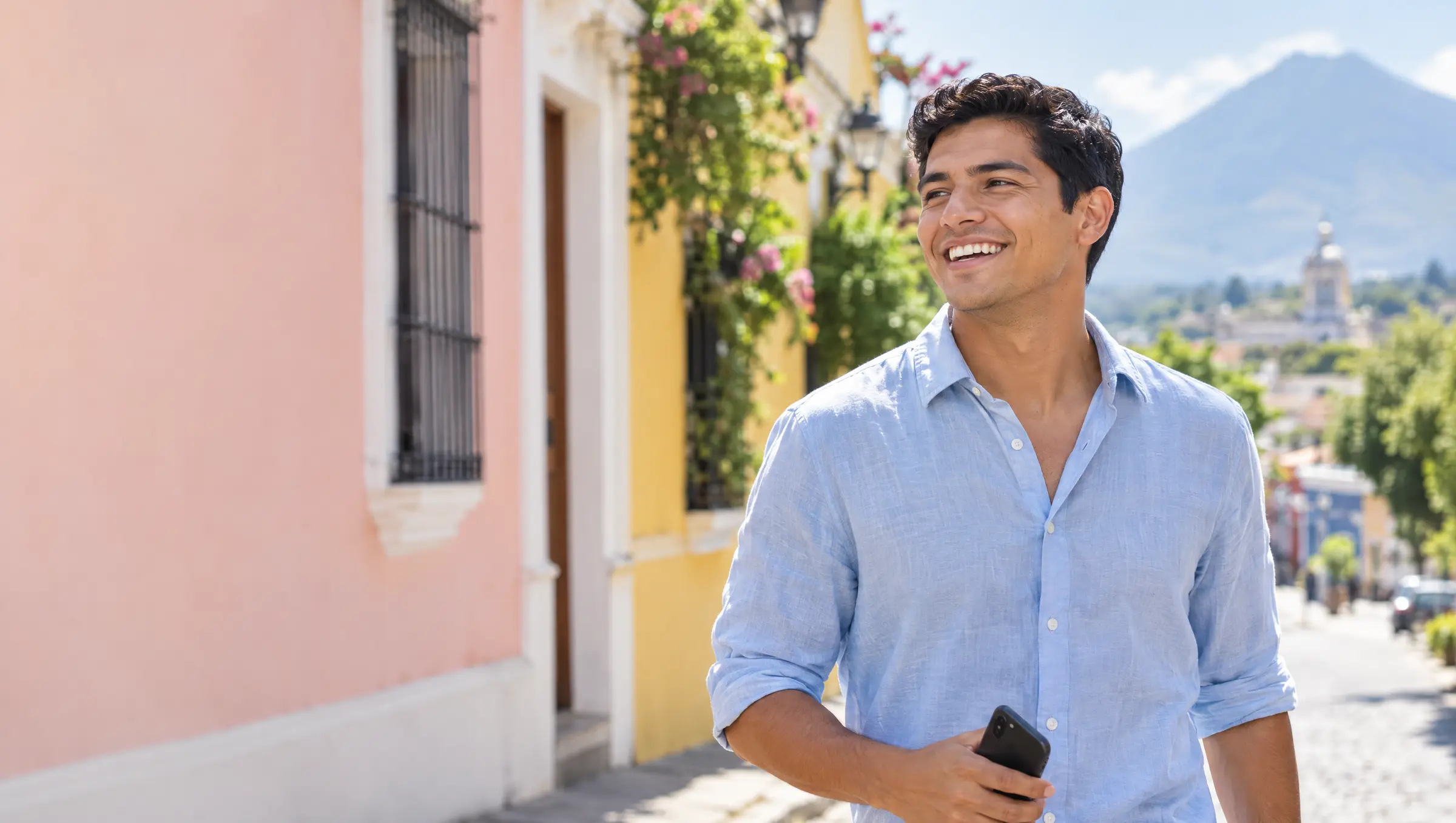 Un hombre sonríe caminando por una calle de fachadas de colores en San Salvador