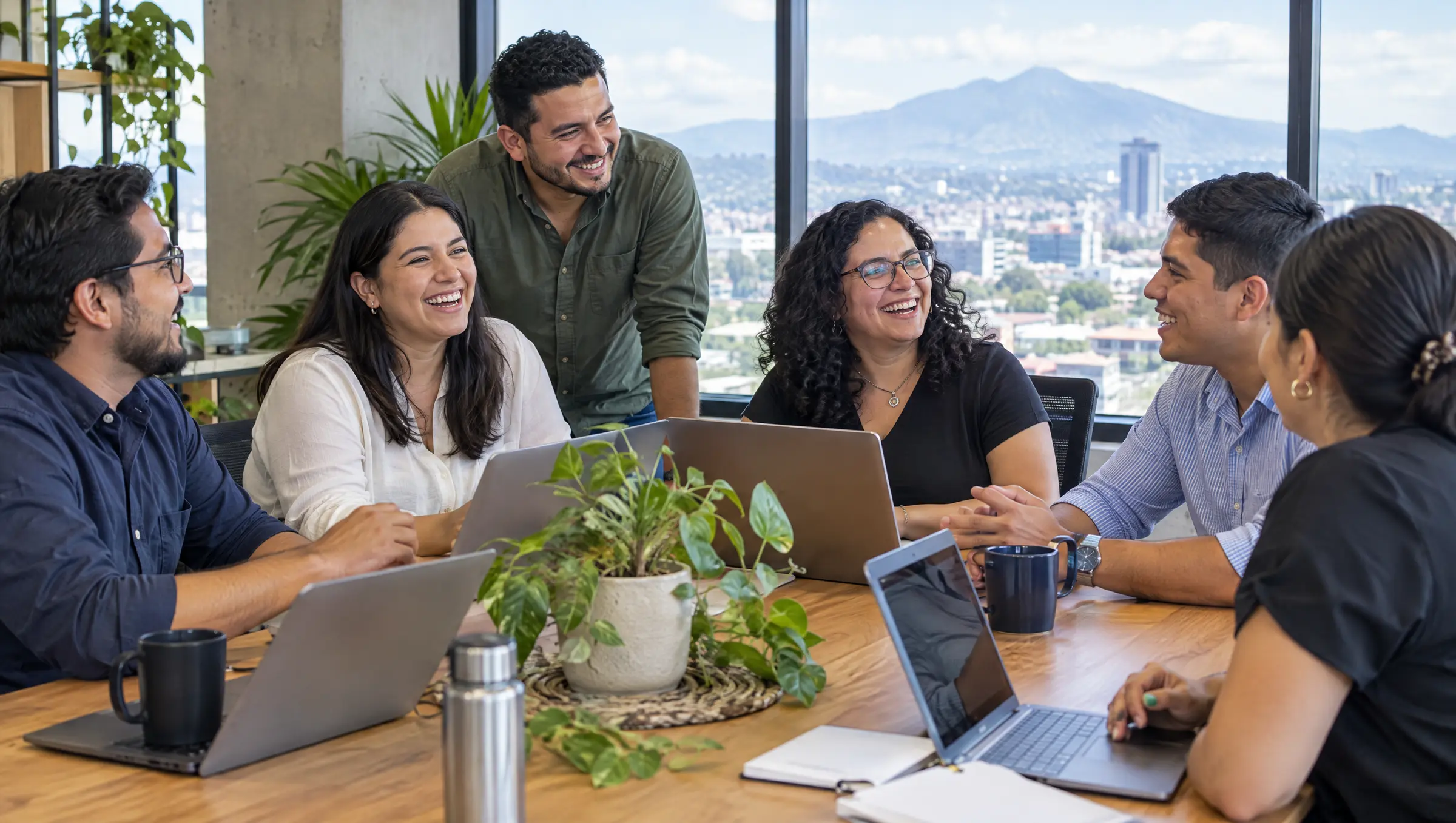 El equipo conversa alrededor de una mesa en una oficina con vista a San Salvador
